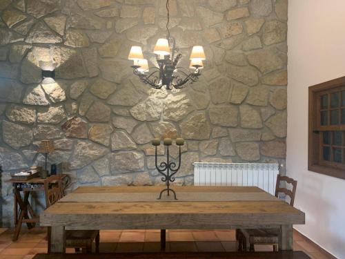 a stone wall with a wooden table and a chandelier at Quinta dos Cedros l Turismo Rural in Covilhã