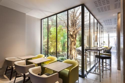 a restaurant with tables and chairs and a large window at Hôtel Duo in Paris