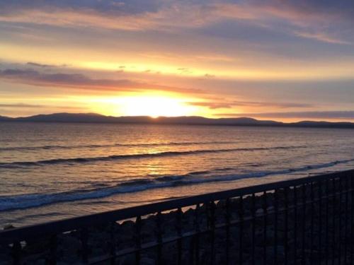 una puesta de sol en la playa con el océano en Delightful Beach Retreat-, en Rossnowlagh