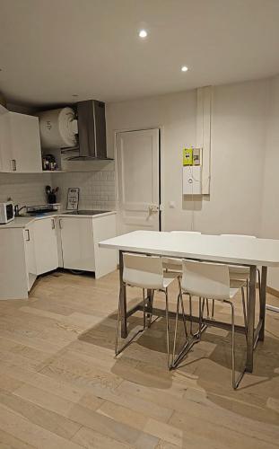 une cuisine avec une table blanche et des chaises dans l'établissement Appartement central 7 eme arrondissement, à Paris