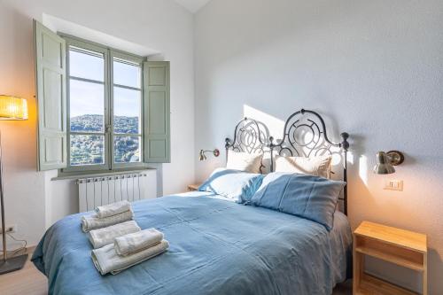 1 dormitorio con cama con sábanas azules y ventana en Manufacto en Petroio