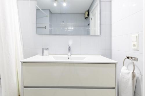 uma casa de banho branca com um lavatório e um espelho em Primera línea de playa con parking - Zarautz em Zarautz