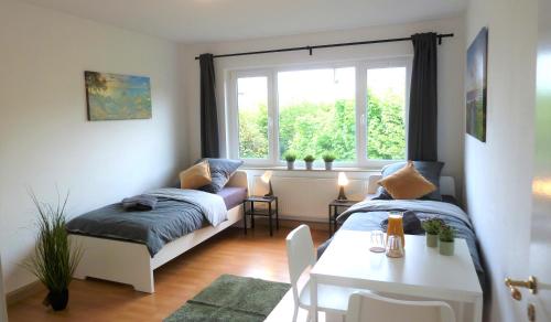 Cette chambre comprend 2 lits, une table et une fenêtre. dans l'établissement Helles Apartment mit Balkon für 5 Personen, à Schwerte