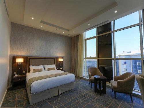 um quarto de hotel com uma cama, cadeiras e janelas em Hams Park Hotel em Jeddah
