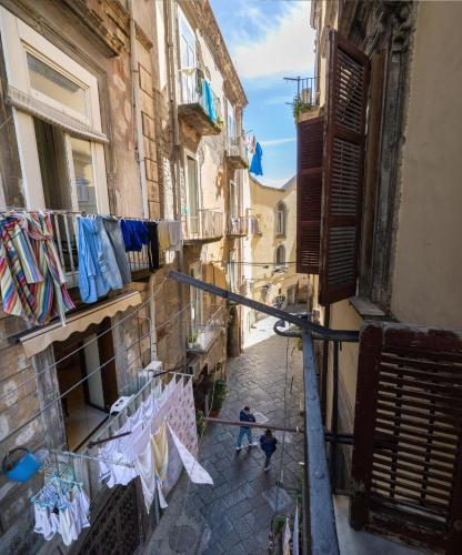 a man walking down a street with clothes drying on a clothes line at Naples Pizza Hostel in Naples