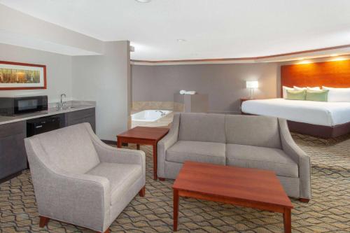 a hotel room with a couch and a bed at Wyndham Garden Fort Wayne in Fort Wayne