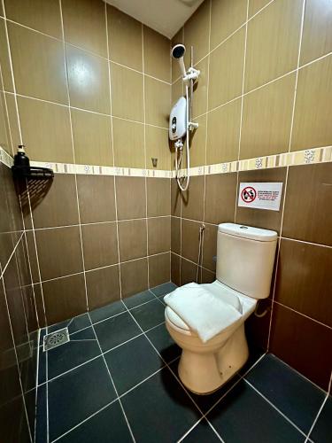 La salle de bains est pourvue de toilettes et d'un téléphone mural. dans l'établissement Swing & Pillows - Apple Hotel Shah Alam, à Shah Alam
