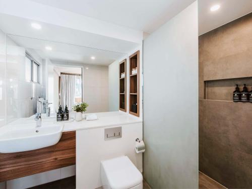 a white bathroom with a sink and a toilet at Parklands Resort in Mudgee