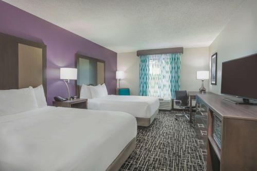a hotel room with two beds and a flat screen tv at La Quinta by Wyndham Covington in Covington