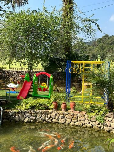 a playground with a slide and a swing set next to a pond at Homestay 68 Hoà Bình in Hanoi