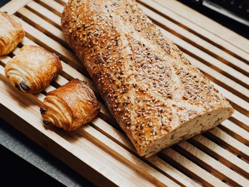 a group of bread and croissants on a cutting board at Hôtel Mercure Rochefort La Corderie Royale in Rochefort