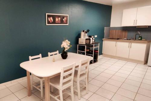 - une cuisine avec une table et des chaises blanches dans la chambre dans l'établissement T3 rez-de-chaussée Centre Douai, à Douai
