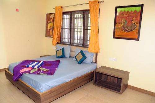 a bedroom with a bed with blue sheets and a window at Franc Villa - Kothagiri in Kotagiri