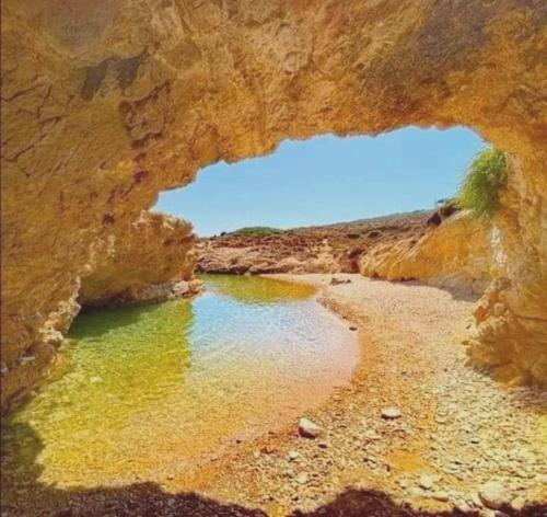 a rock cave with a pool of water on a beach at Kalypso Apartments in Lipsoi