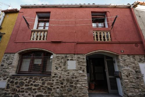 Vilamaniscle的住宿－Ca La Serena - Sant Josep，红色的建筑,设有两扇窗户和一扇门