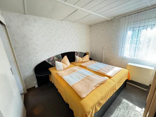 a bedroom with a large bed with yellow sheets at Feriendomizil im Dünenwald in Trassenheide