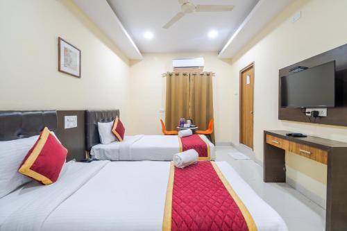 a hotel room with two beds and a flat screen tv at Lemonridge Hotels Kukatpally in Hyderabad
