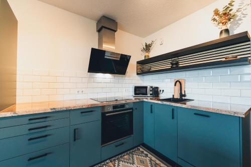 a kitchen with blue cabinets and a sink at Hunsrück Valley View Apartment with Cedar SAUNA in Bruschied