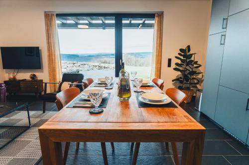 a wooden table with glasses and a bottle of wine at Hunsrück Valley View Apartment with Cedar SAUNA in Bruschied