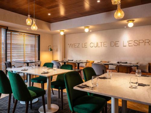 een eetkamer met tafels en groene stoelen bij Mercure Paris Montparnasse Pasteur in Parijs