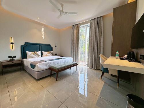 a bedroom with a bed and a desk and a table at Hotel Baga Bliss By Celestiial Hospitality, Baga North Goa in Goa