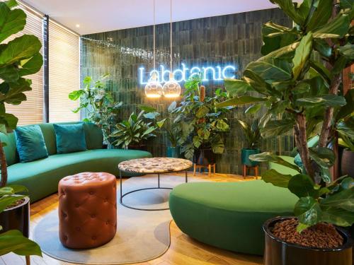 a lobby with green furniture and potted plants at Mercure Paris Montparnasse Pasteur in Paris