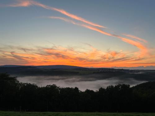 a sunset with clouds in a field with the sky at Hunsrück Valley View Apartment with Cedar SAUNA in Bruschied