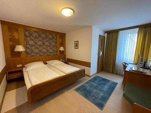 a bedroom with a bed and a desk with a television at Hotel Württemberger Hof Garni in Rottenburg