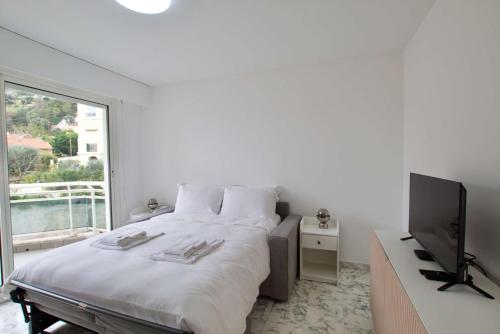 ein weißes Schlafzimmer mit einem Bett und einem TV in der Unterkunft Cosy studio aperçu mer Monaco border in Beausoleil