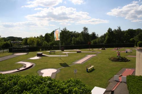 Pension / Gaststätte zum Minigolfplatz في Versmold: حديقة بها مقاعد وعلام على العشب