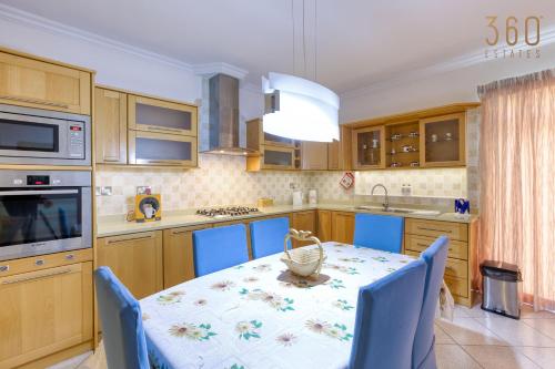 een keuken met een tafel met blauwe stoelen eromheen bij Charming 3BR Apt with Breathtaking Sea Views by 360 Estates in Birżebbuġa