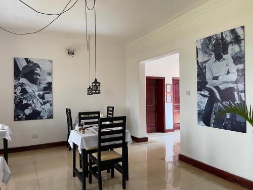 a dining room with a table and chairs and pictures on the walls at The Jewel and the Lake in Jinja