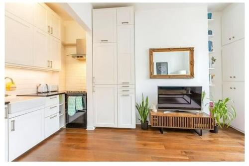 a kitchen with white cabinets and a mirror on the wall at Stylish, 2 Bed Apartment, Muswell Hill in London