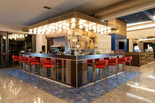 a bar with red bar stools in a restaurant at Doubletree by Hilton Milan Malpensa Solbiate Olona in Solbiate Olona