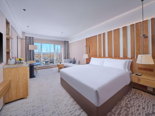a bedroom with a large white bed and a living room at DoubleTree by Hilton Changbaishan Hot Spring in Antu