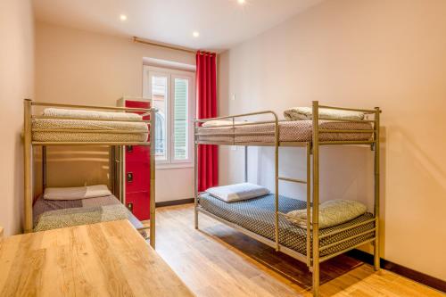 two bunk beds in a room with a table at Villa Saint Exupery Beach Hostel in Nice
