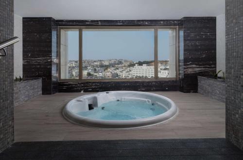 a large bath tub in a bathroom with a large window at DoubleTree by Hilton Muscat Qurum in Muscat