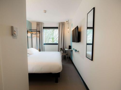 - une chambre d'hôtel avec un lit et un miroir dans l'établissement Greet Hotel Brest Aéroport, à Guipavas