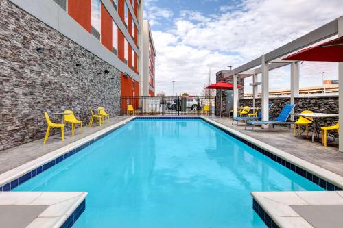 a swimming pool with yellow chairs and a building at Home2 Suites By Hilton Tulsa Airport in Tulsa