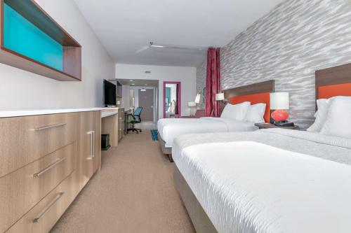 a hotel room with two beds and a flat screen tv at Home2 Suites By Hilton Tulsa Airport in Tulsa