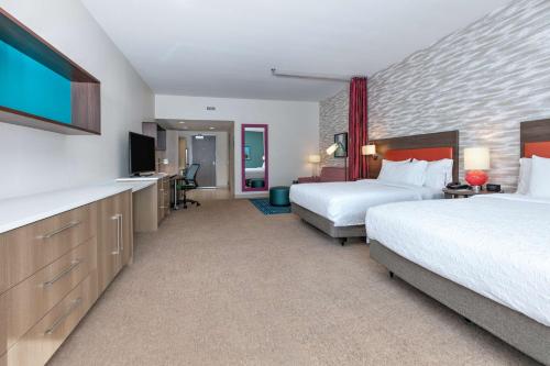 a hotel room with two beds and a flat screen tv at Home2 Suites By Hilton Tulsa Airport in Tulsa