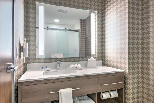 a bathroom with a sink and a large mirror at Home2 Suites By Hilton Tulsa Airport in Tulsa