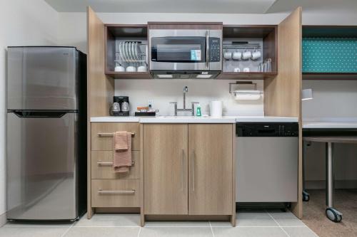 a kitchen with a refrigerator and a microwave at Home2 Suites By Hilton Tulsa Airport in Tulsa