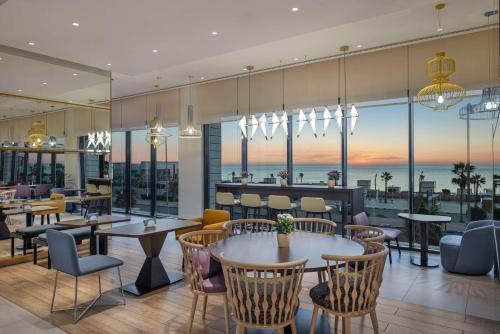 um restaurante com mesas e cadeiras e vista para o oceano em Hampton By Hilton Kuwait Salmiya em Kuwait