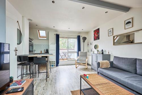 un salon avec un canapé et une cuisine dans l'établissement Au Jardin de Mel - Appt à moins d'1 km de la plage, à Courseulles-sur-Mer