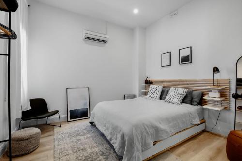 a white bedroom with a bed and a chair at Your home on Smith St Collingwood (With Parking) in Melbourne