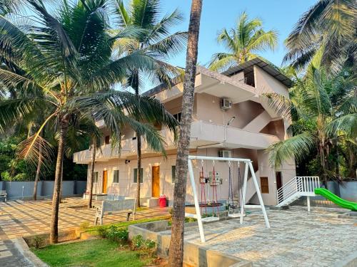 une maison avec des palmiers et une aire de jeux dans l'établissement The Saltwater Homestay, à Udupi