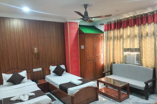 a room with two beds and a couch and a table at HOTEL RIZ VARANASI in Varanasi
