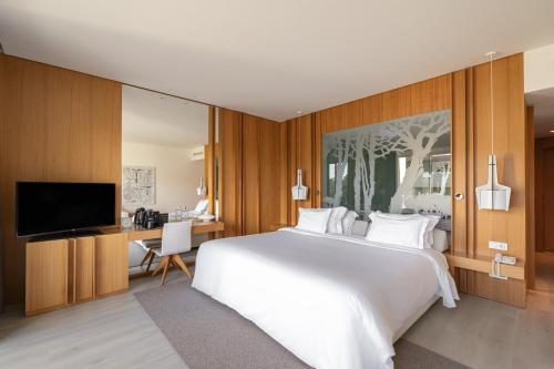 a bedroom with a large white bed and a desk at Onyria Marinha Boutique Hotel in Cascais