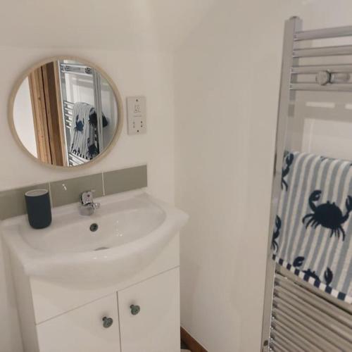 a white bathroom with a sink and a mirror at Heart of Kernow Holidays in Bugle